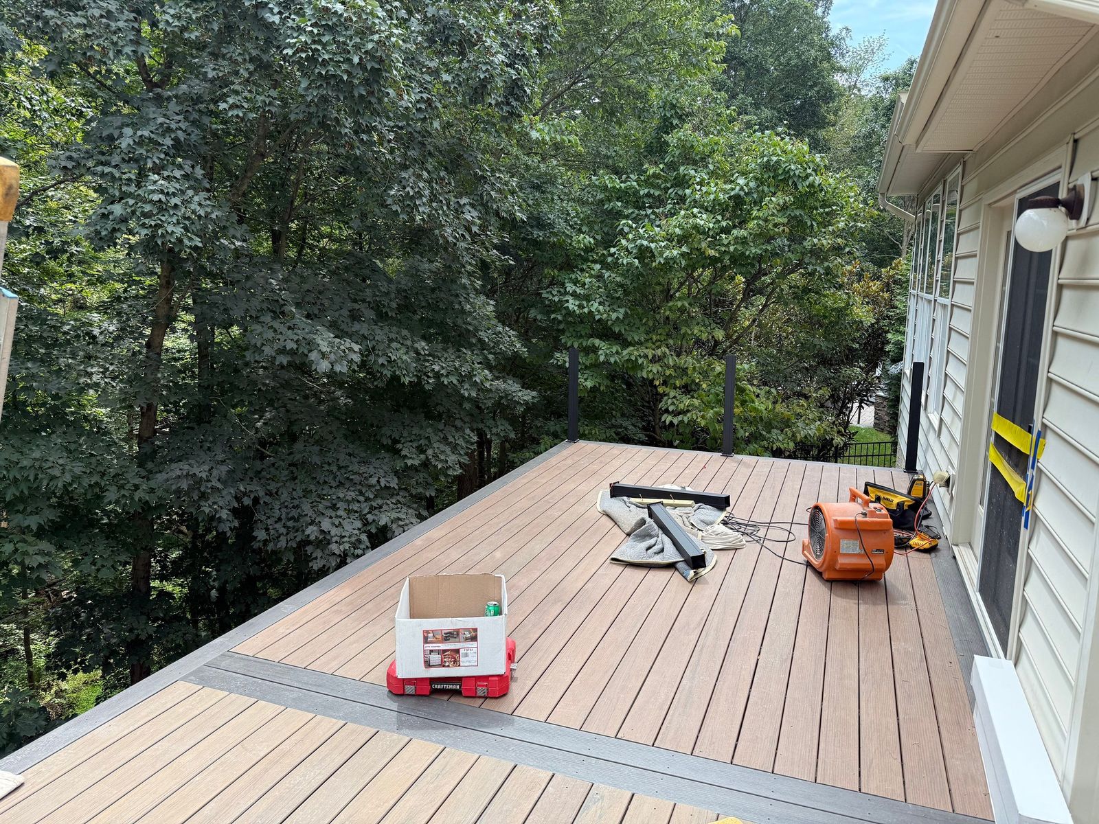 Brown composite deck with gray picture-frame border under construction at a wooded Main Line home in Newtown Square, PA