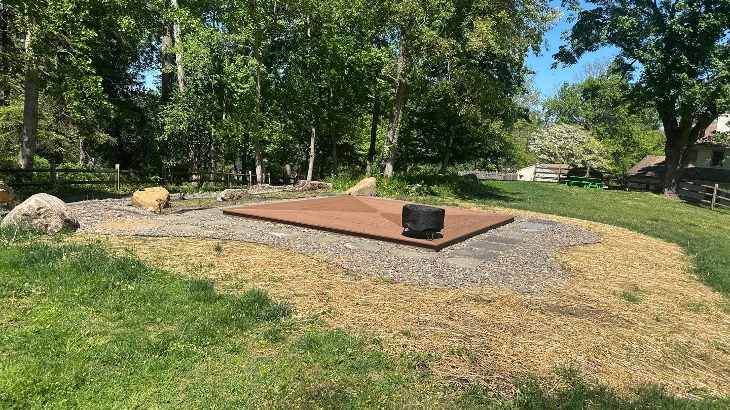 Low brown composite ground-level deck platform in a wooded backyard near the Main Line, PA