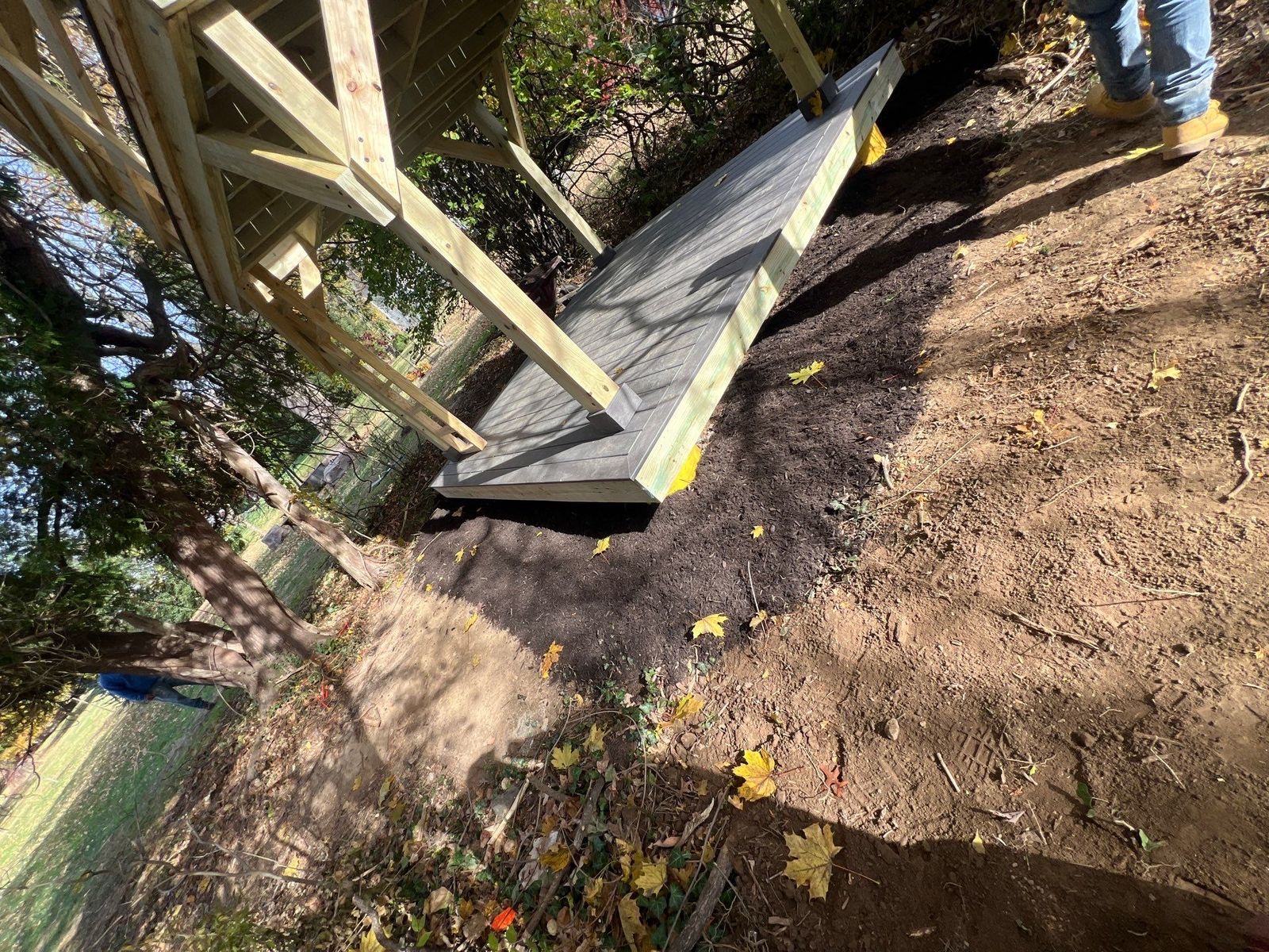 Wood-framed access ramp with composite decking descending from a backyard deck in rural Chester County PA