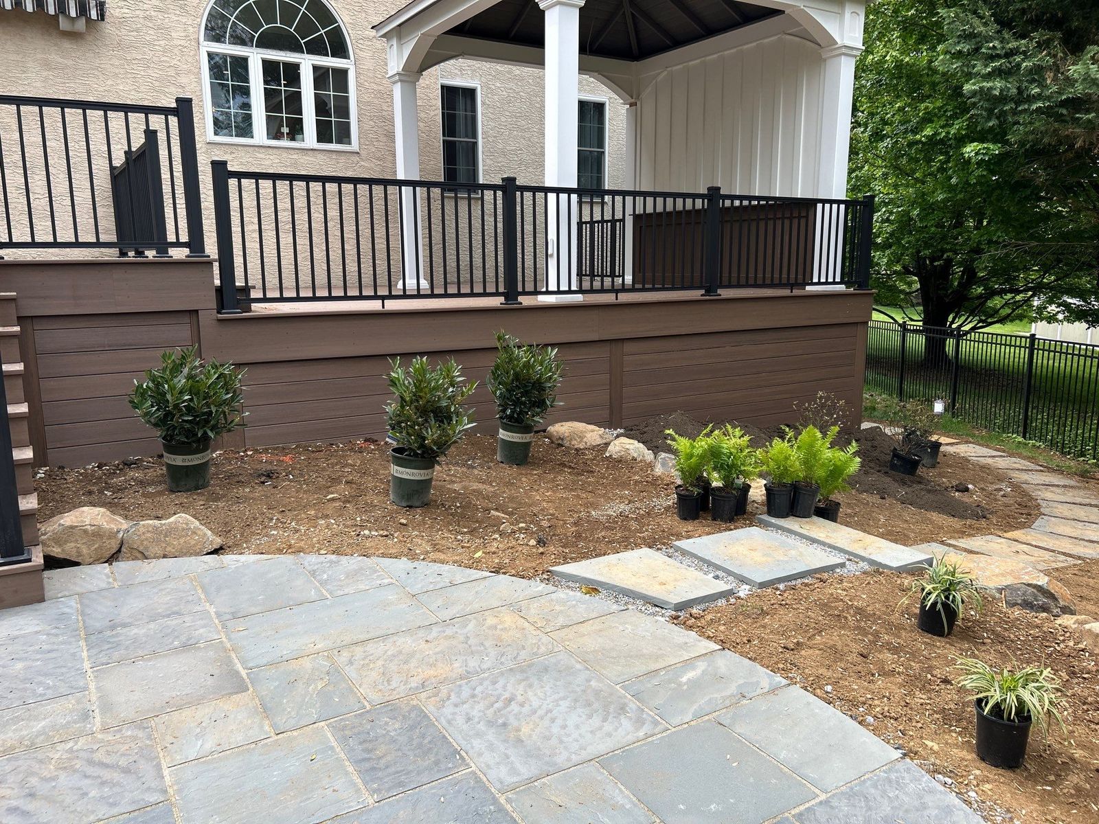 Raised composite deck with brown skirting beside a new bluestone paver patio at a Main Line PA backyard
