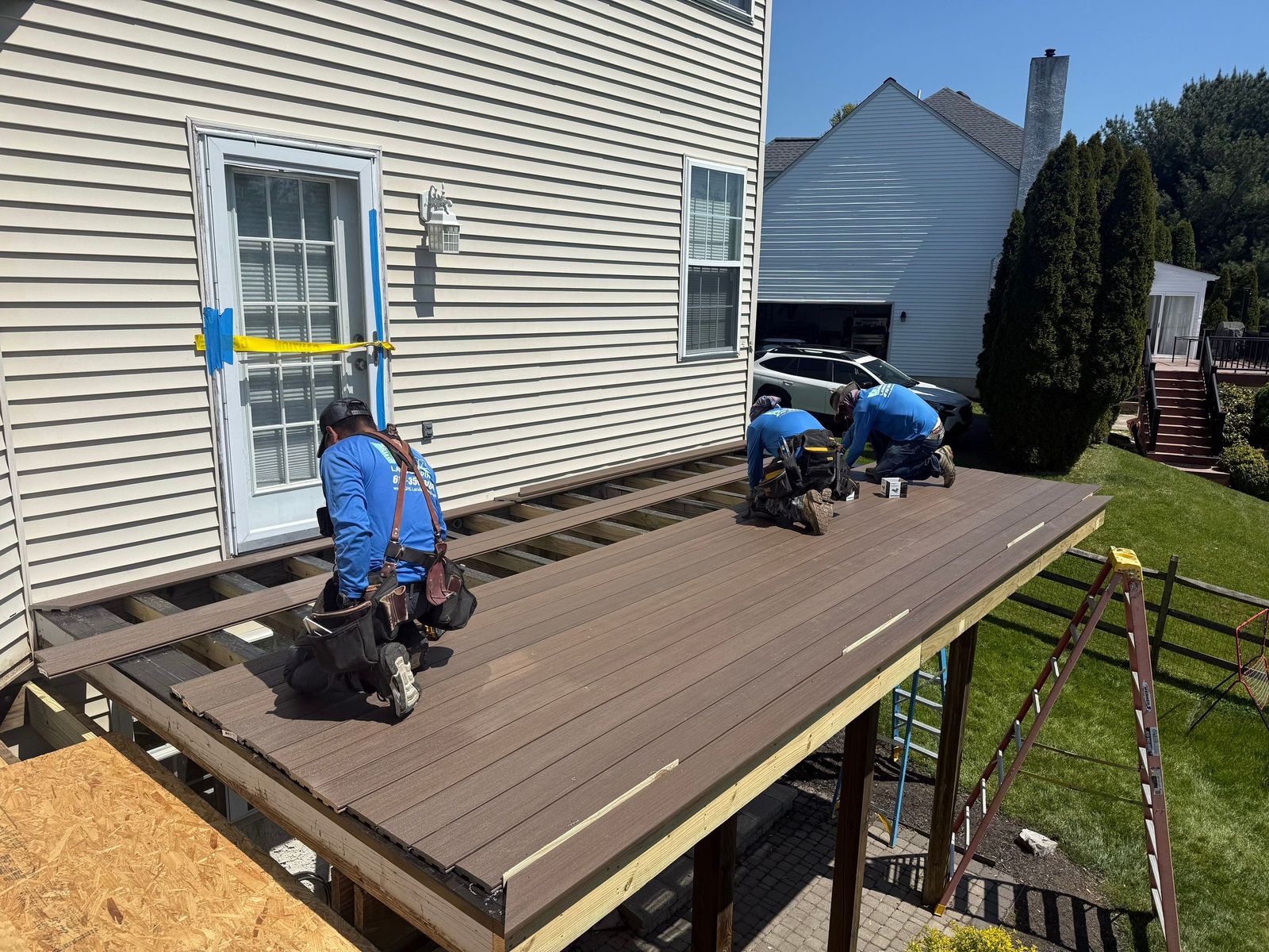 JHL crew installing dark brown composite decking on an elevated deck at a suburban Delaware County PA home