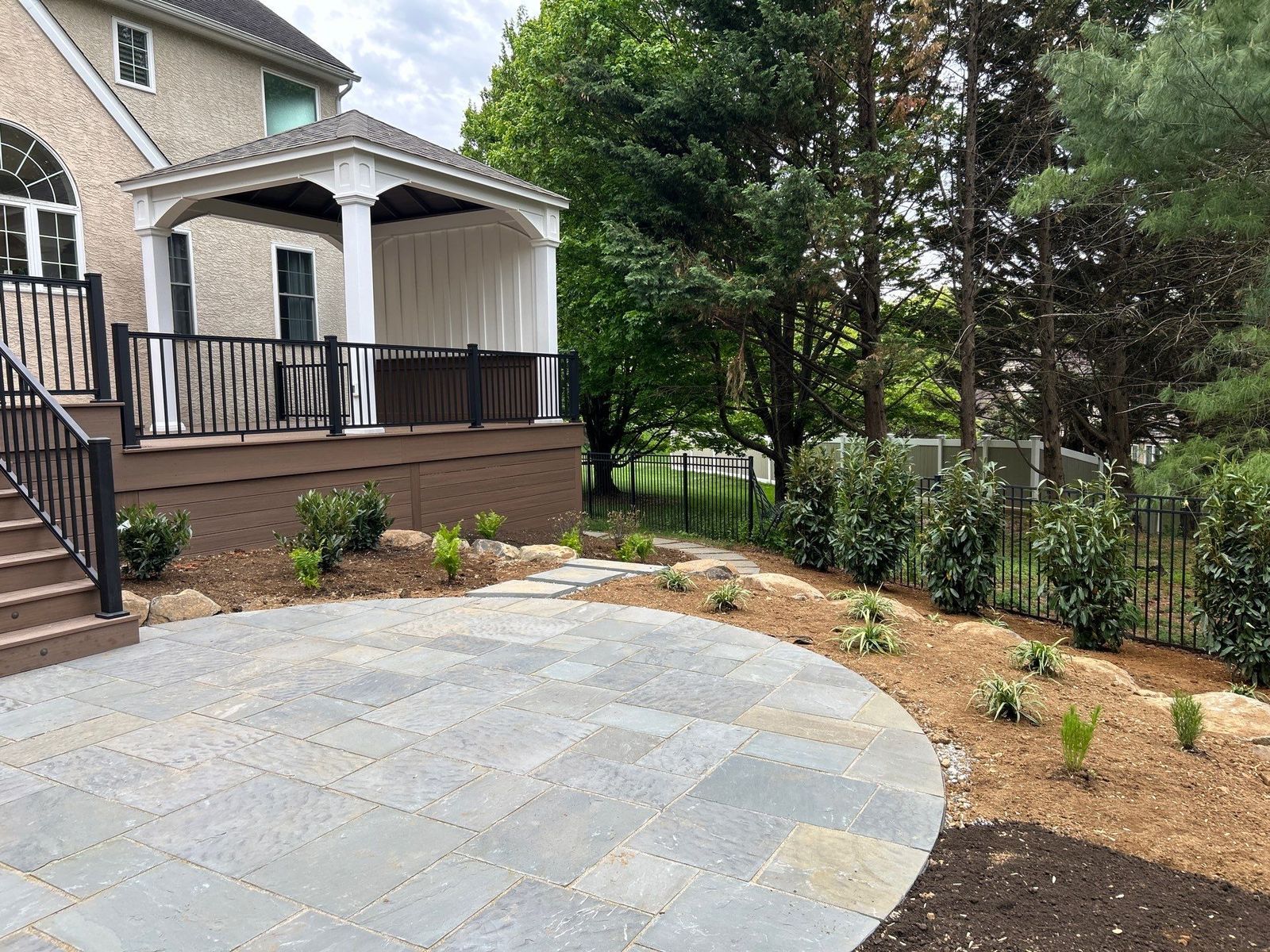 Composite deck with covered porch and curved bluestone patio at a Newtown Square PA backyard