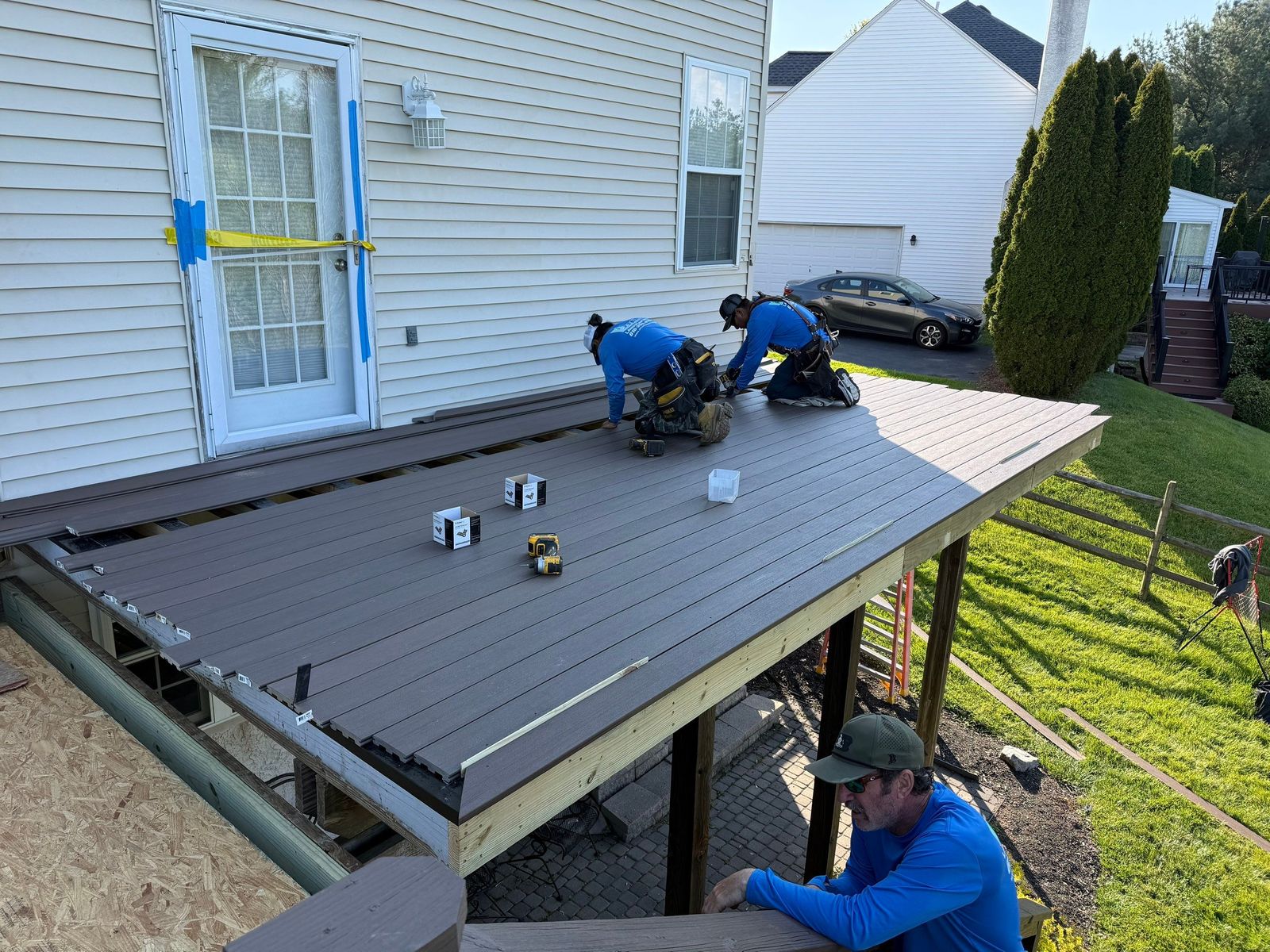 JHL crew installing brown composite decking on an elevated deck at a suburban Main Line PA home