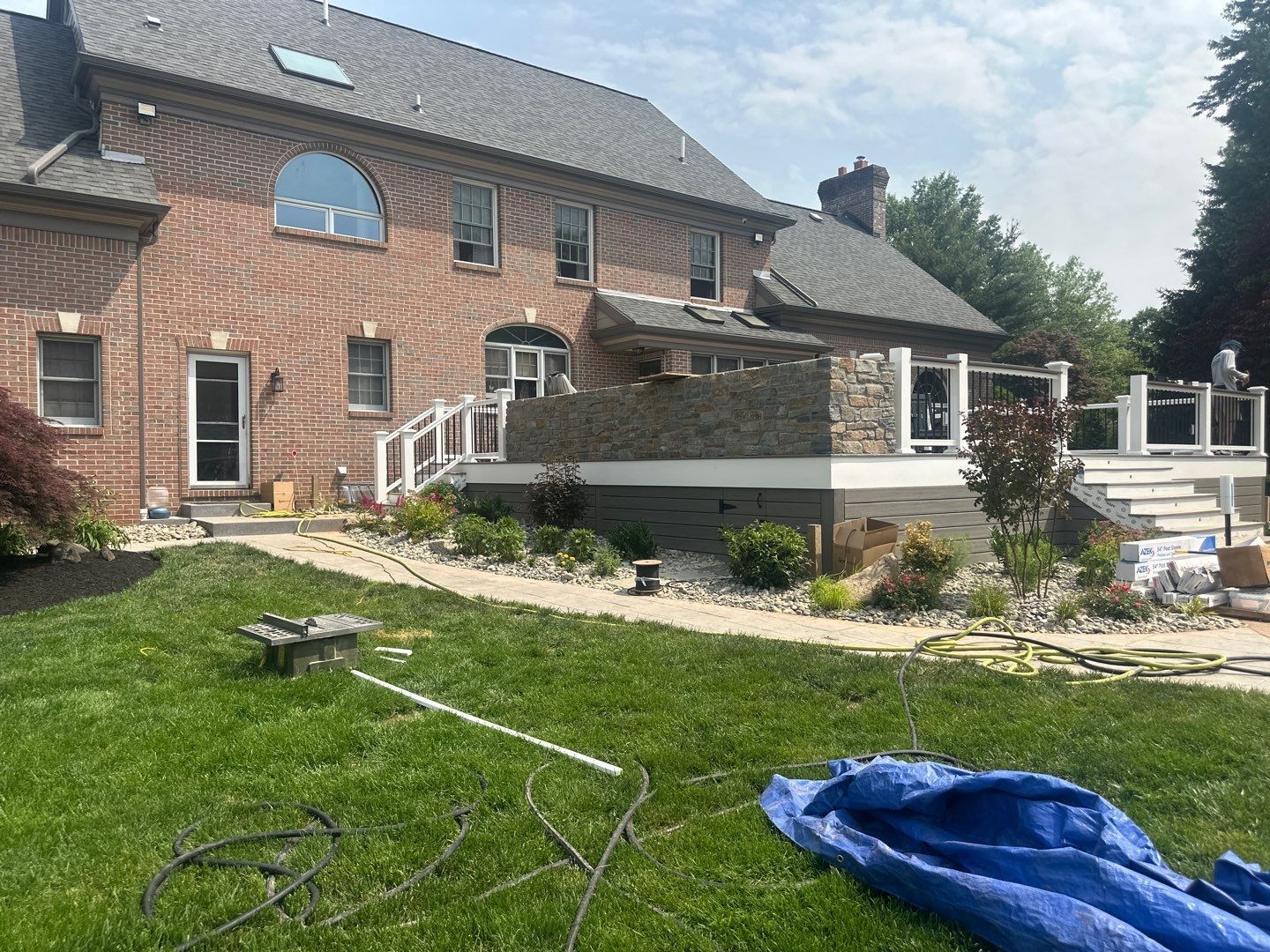 Raised composite deck with stone veneer walls under construction at a large brick Main Line PA home