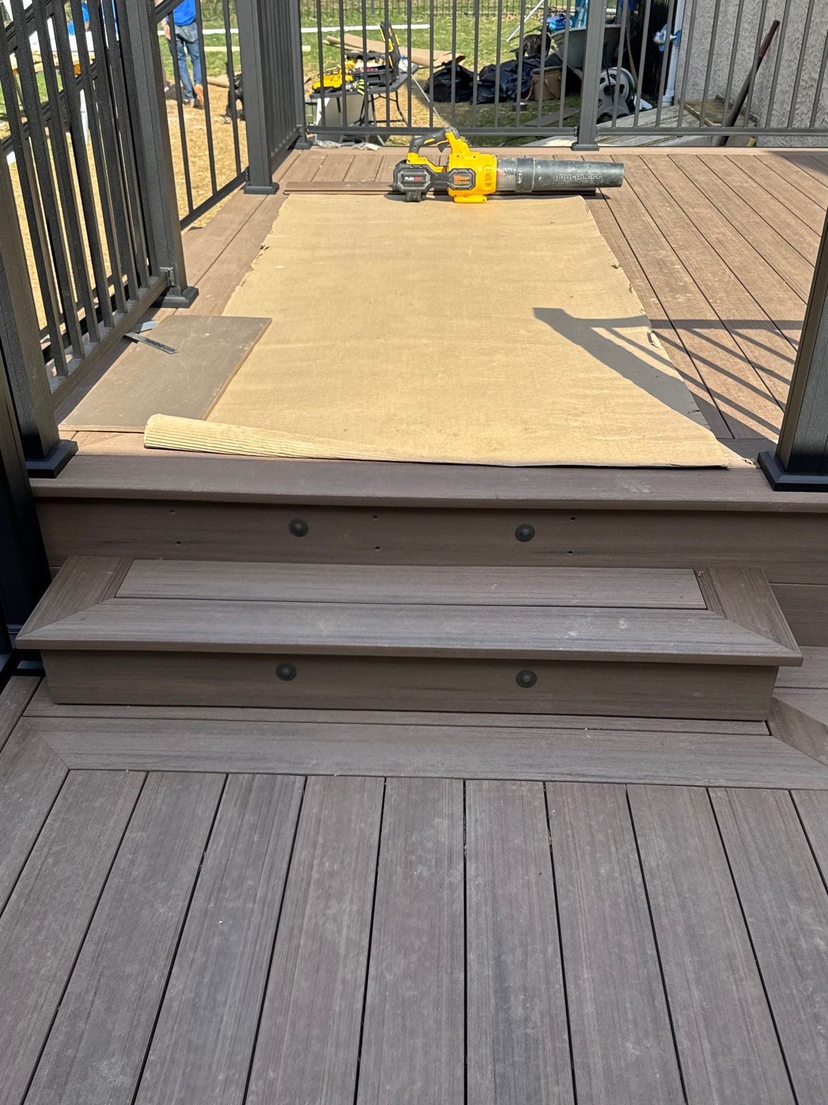 Brown composite deck with wide stairs and black aluminum railing at a Main Line PA backyard home