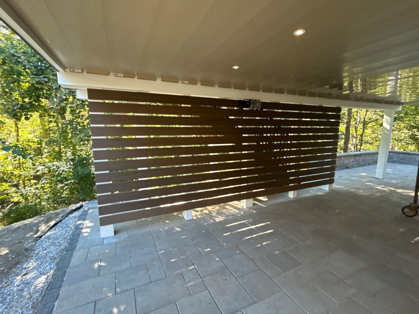 Covered deck with a horizontal brown composite privacy screen over a paver patio in Chester County, PA