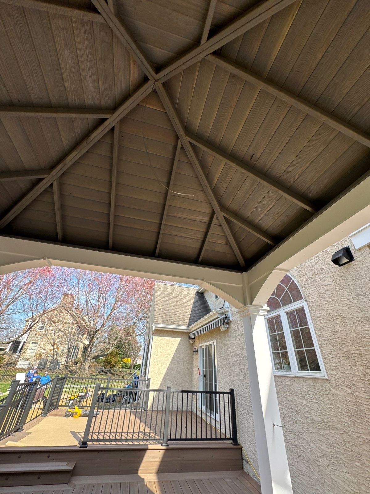 Covered porch with vaulted wood ceiling and black aluminum railing on a stucco home in Delaware County PA