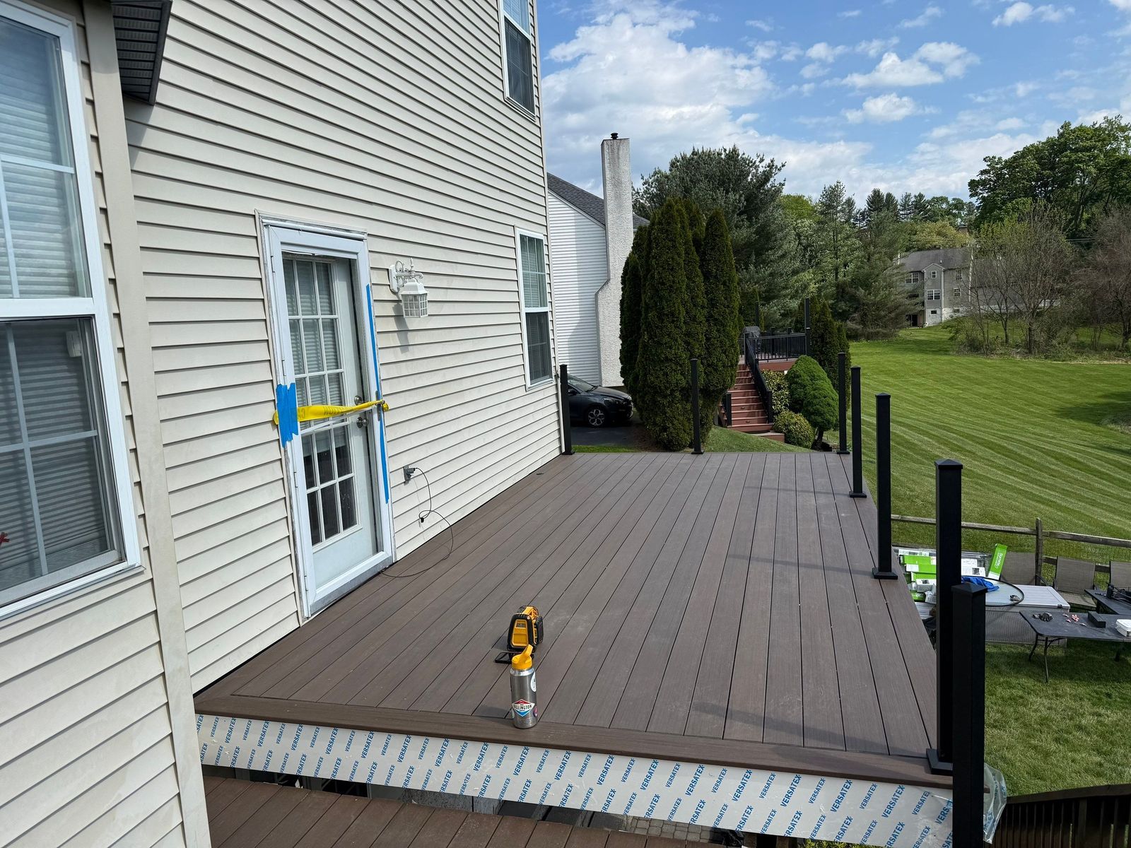 Dark brown composite deck under installation with black aluminum railing posts at a Delaware County home near Newtown Square, PA