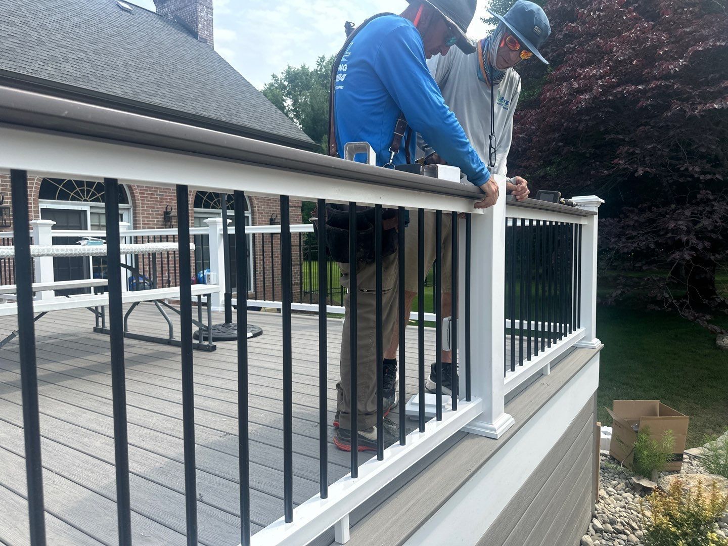JHL crew installing black aluminum and white deck railing on a composite deck at a brick Main Line PA home