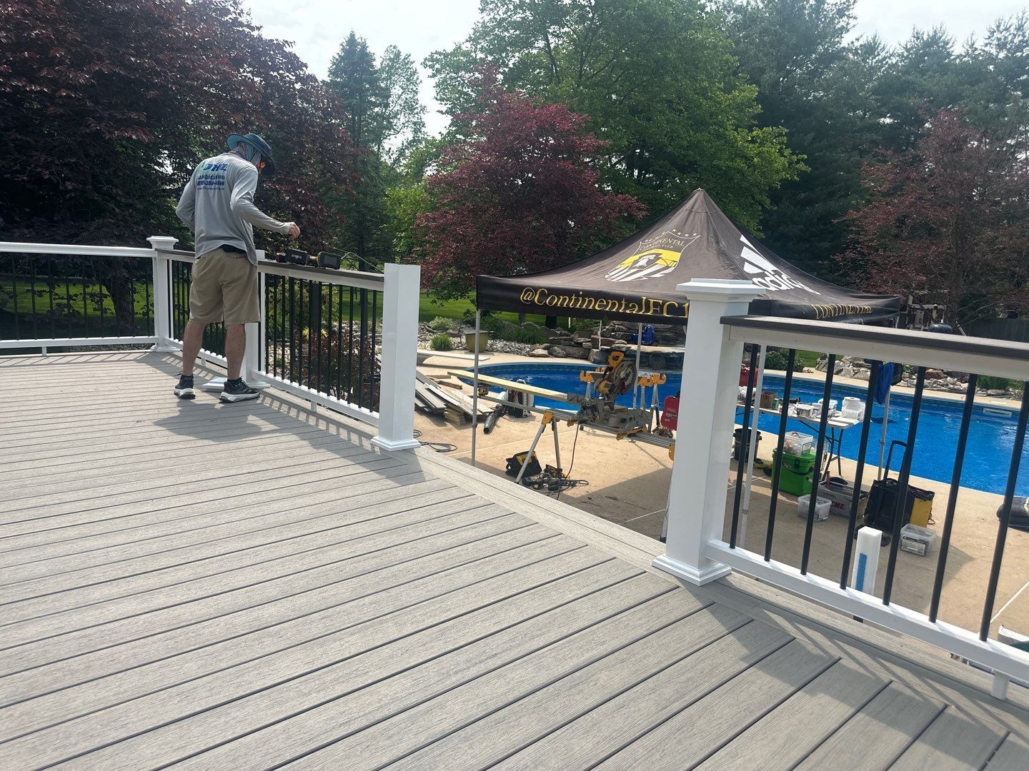 JHL worker installing black aluminum and white railing on a composite pool deck at a Chester County PA home