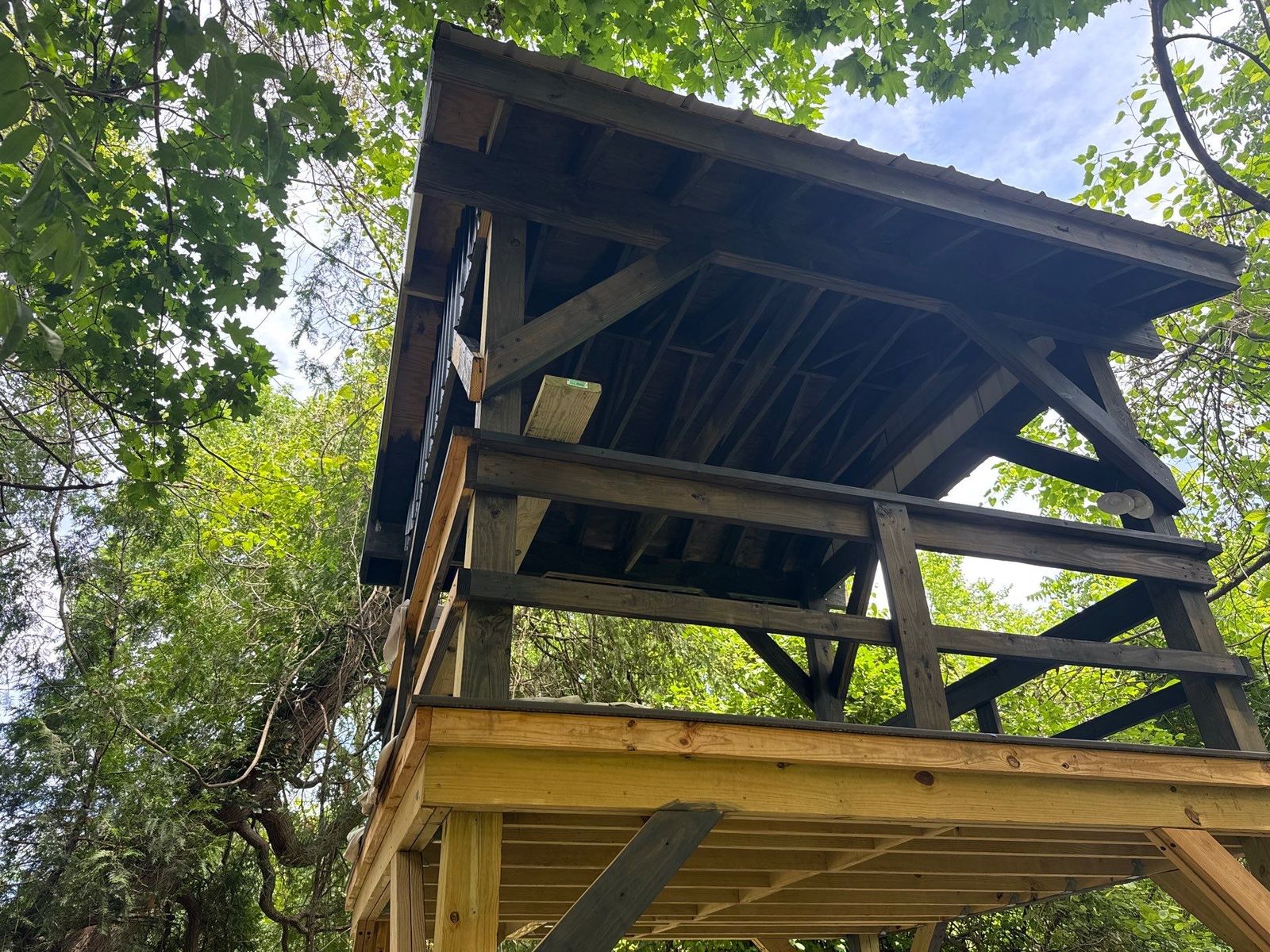 Elevated wood treehouse-style deck with peaked timber roof under construction in a wooded Chester County PA yard