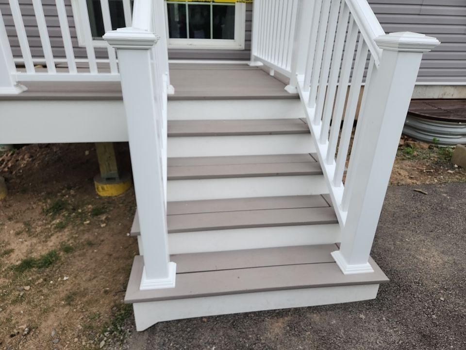 Gray composite deck stairs with white PVC railing leading to the driveway of a Main Line, PA home