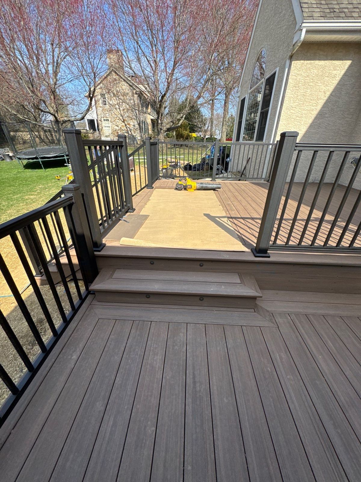 Two-level brown composite deck with black aluminum railing and a step transition at a suburban Delaware County PA home