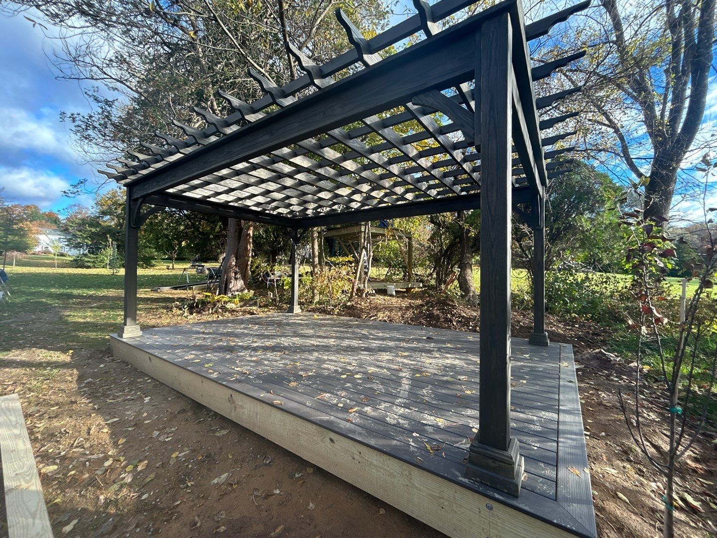 Newly built dark pergola over a gray composite deck platform in a Main Line PA backyard