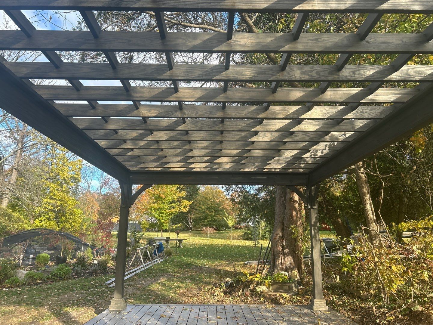 Dark-stained pergola with open lattice roof over a composite deck in a Main Line PA backyard